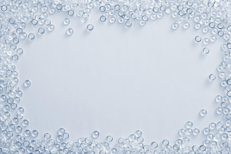 Textured background composed of clear beads that frame the border on light blue colored table