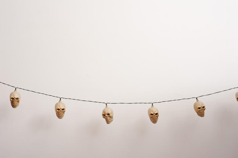 String of creepy ghoulish unlit Halloween skull lights over a white background with copy space for your festive message