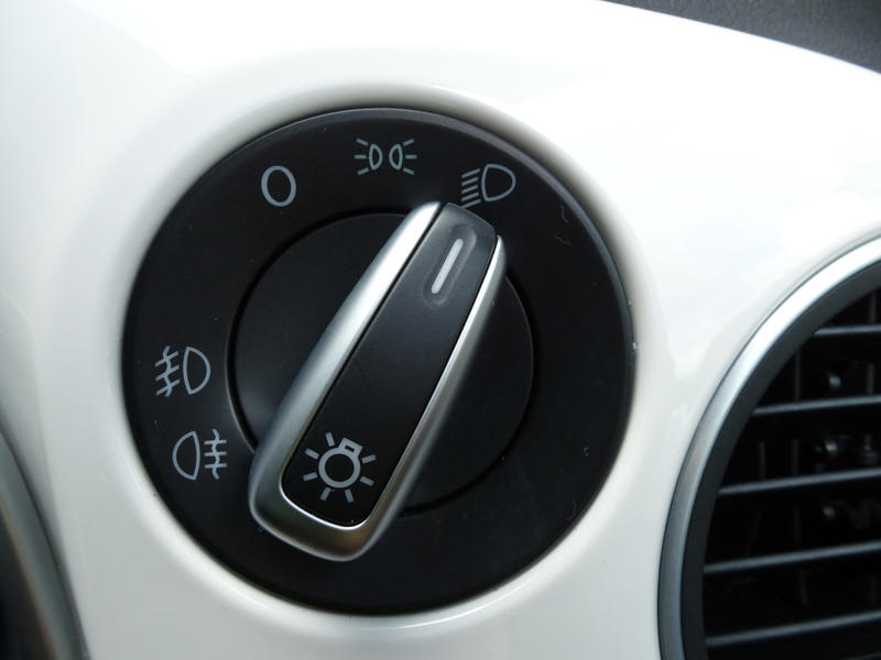 Headlight control on a motor car on a white dashboard set to full beam in a close up view
