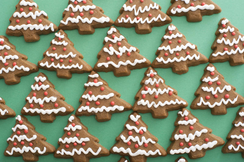 Iced gingerbread cookie background pattern with delicious traditional Christmas tree shaped biscuits on green in a full frame view