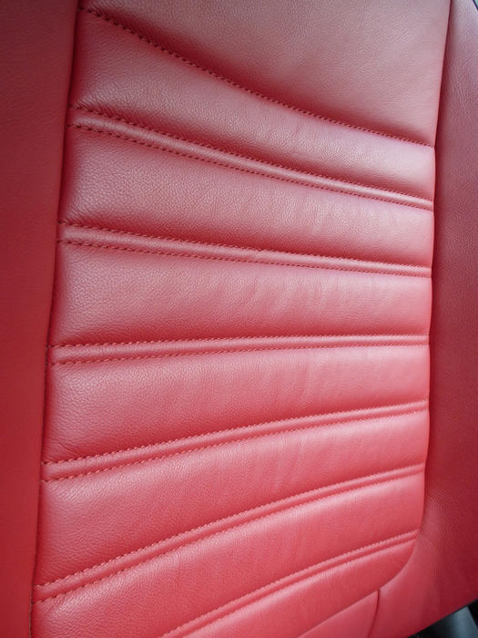 Red leather car seat texture with a ridged design for comport in an oblique angle view