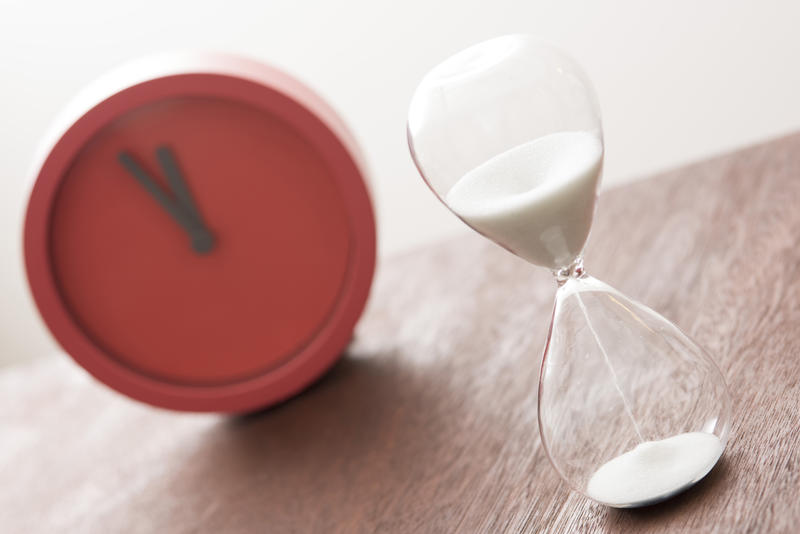 Counting down cooking time in the kitchen with a glass egg timer or modern red timer clock in a tilted angle view with focus to the hourglass