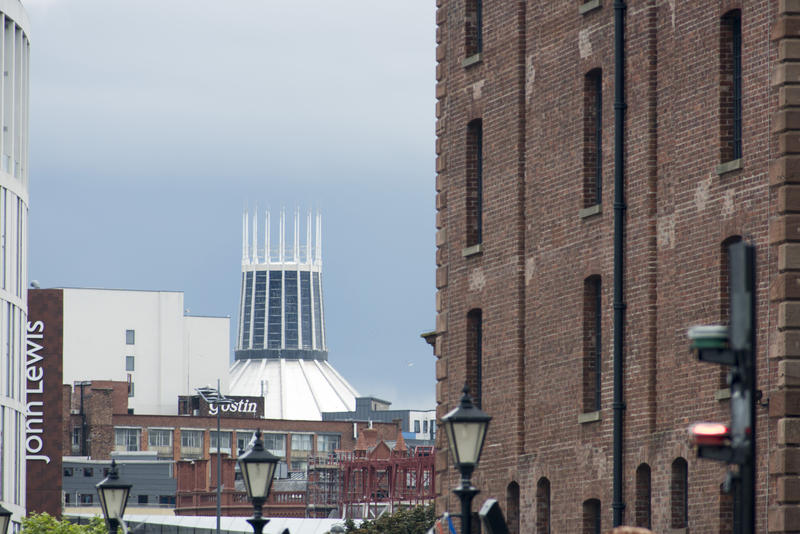 Tall pointy spire of Liverpool Catholic Cathedral in the far distance, behind industrial and residential buildings.
