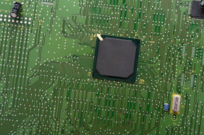 Blank black microcontroller on green motherboard surface
