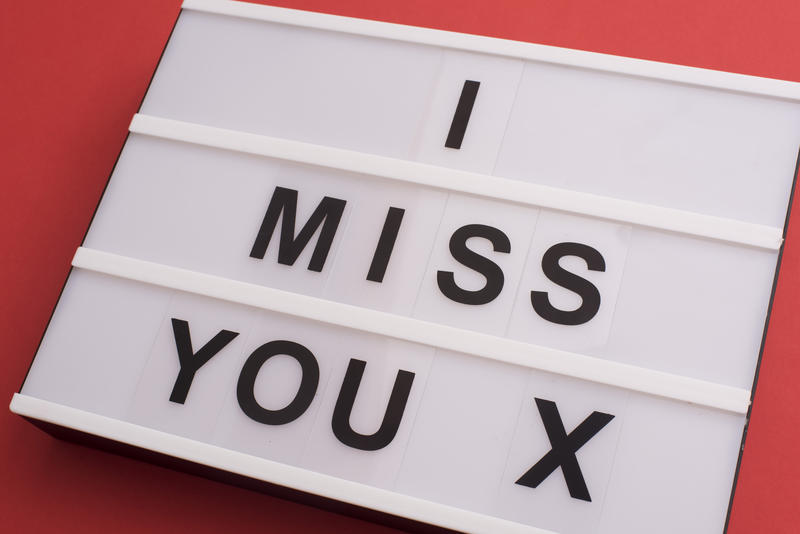 Sentimental tender - I Miss You - message with an X kiss in black text on a small light box on a deep red background conceptual of Love, friendship and Valentines Day