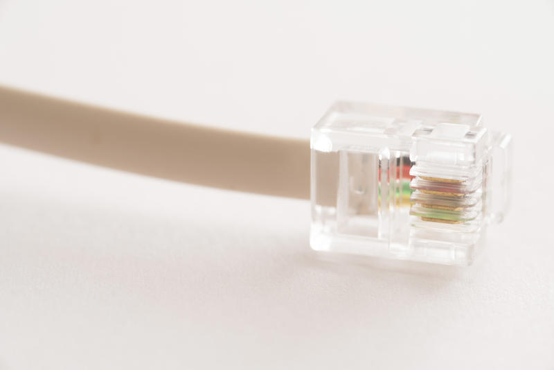 Transparent plastic connector on a telephone cable on a white background with copy space in a telecommunications concept