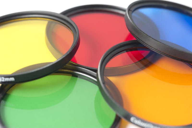 Set of colorful optical photographic filters in red, green, yellow, orange and blue laid out in an overlapping layer viewed low angle close up