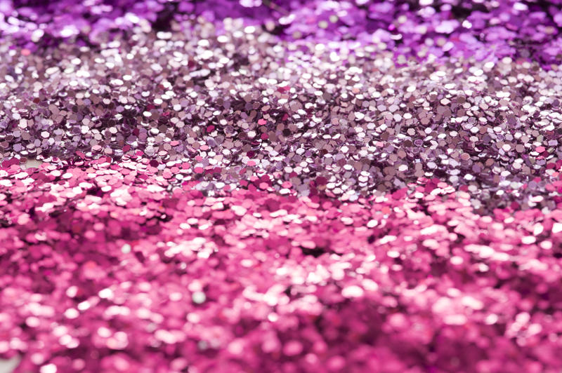 A horizontal magenta and purple coloured background of glitter