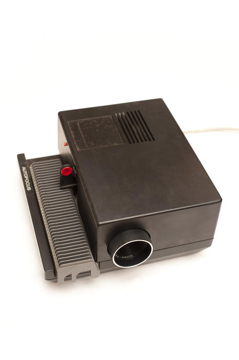 Old slide projector on white with an empty removable tray viewed high angle