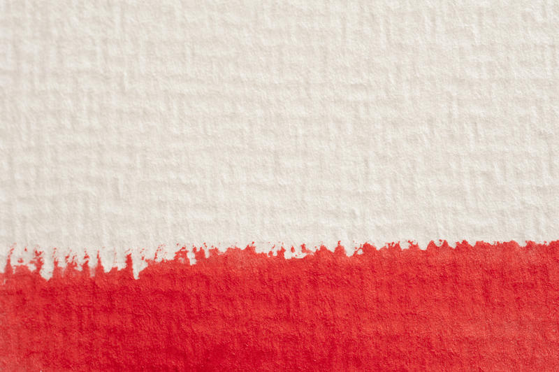 Extreme macro close up view on thick red watercolor paintstroke on textured canvas paper