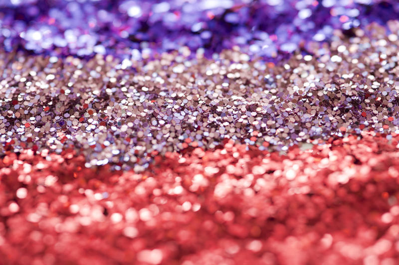 Extreme Close Up of Sparkling Glitter Background Arranged in Colors of Red, Pink and Purple - Celebratory Sequin Background Arranged Full Frame in Stripes in Selective Focus