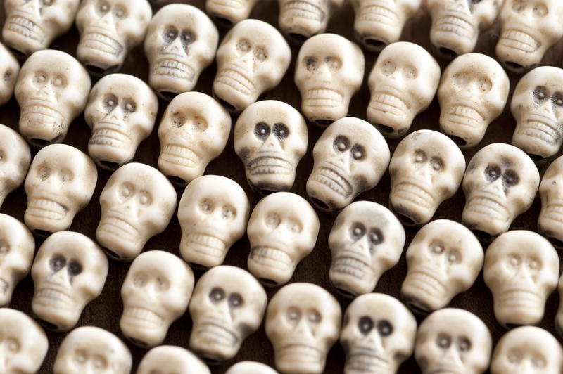 Neatly arranged white plastic skull background for Halloween, horror, piracy, death or genocide themed concepts in a close up full frame view