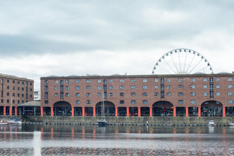 View across the water of the famous Albert Dock, Liverpool, UK showing the historical listed buildings and ferris wheel