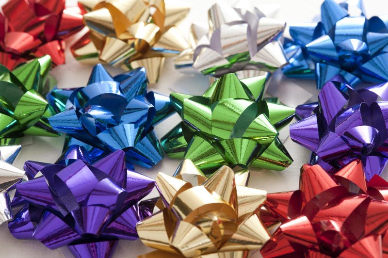 Multiple colorful decorative bows made from shiny ribbon for decorating festive gifts and packaging, full frame view