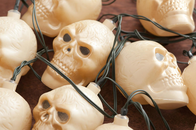 Bundle of plastic toy skull party lights for Halloween in a close up view in a tangle of wires with focus to the central face