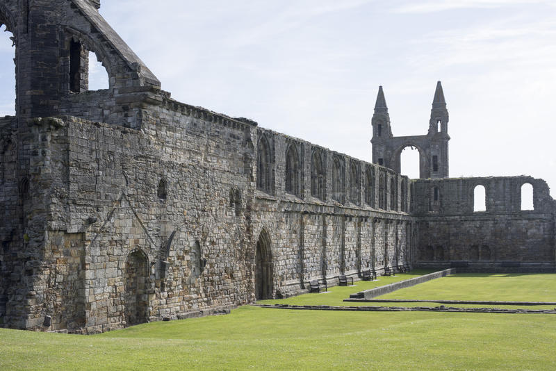 World famous stone wall remains of the historic Saint Andrews cathedral surrounded by green grass in Scotland