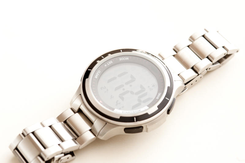 Gents stainless steel wrist watch with a bracelet strap lying diagonally on a white background with copyspace, high angle view