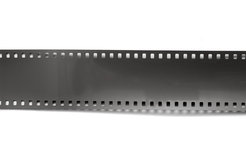Open exposed role of 35mm film lying across a white background with copy space, viewed from above