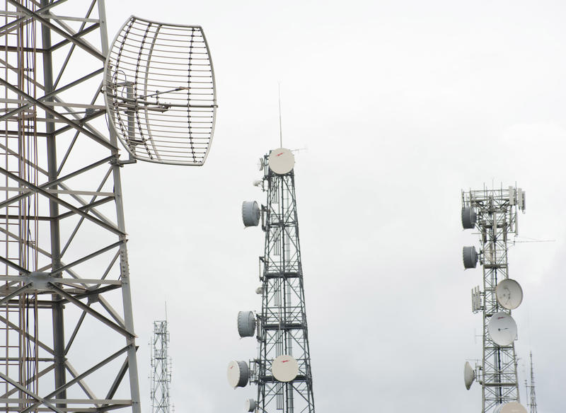 Four telecoms communication masts with transmitters and receivers for the mobile phone infrastructure on a misty cloudy grey day