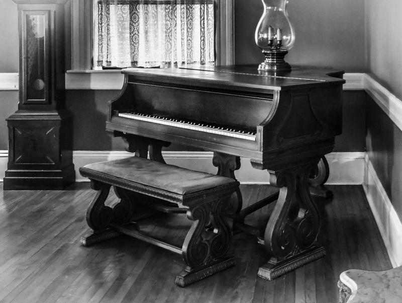 <p>Black and white photo of an old grand piano made to look like an antique image.</p>
