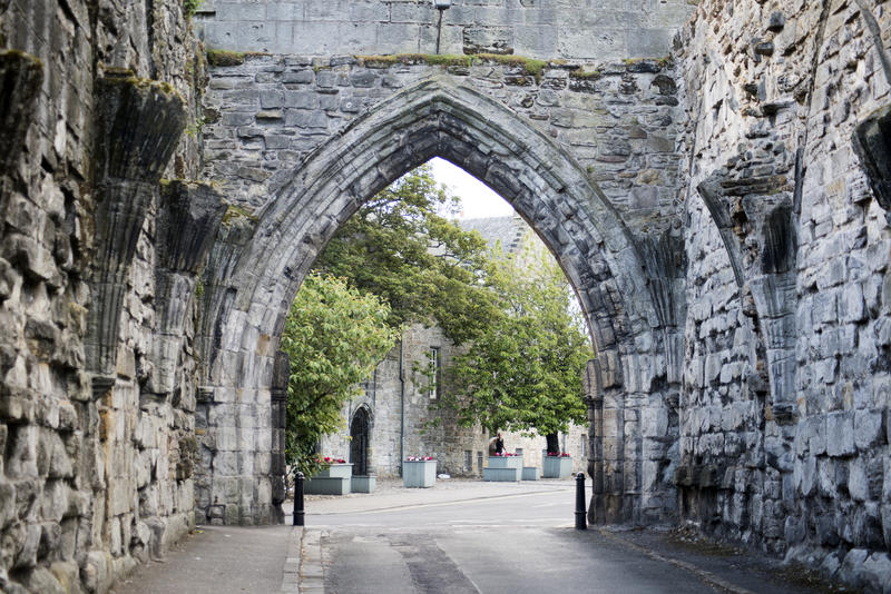 Ancient Gothic arch St Andrews Cathedral ruins in St Andrews Scotland with a street running through the old stone walls in a travel concept
