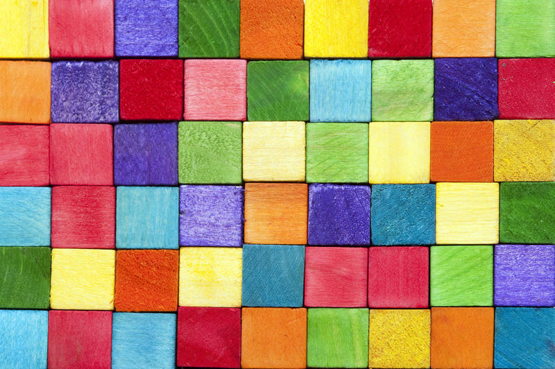 Colorful background texture of wooden toy building blocks in the colors of the rainbow neatly arranged in rows in a full frame view