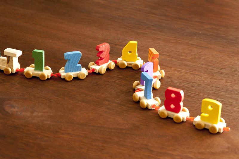 Colorful wooden numbers train with little carriages each bearing a number 1 through 9 for teaching kids basic counting and arithmetic