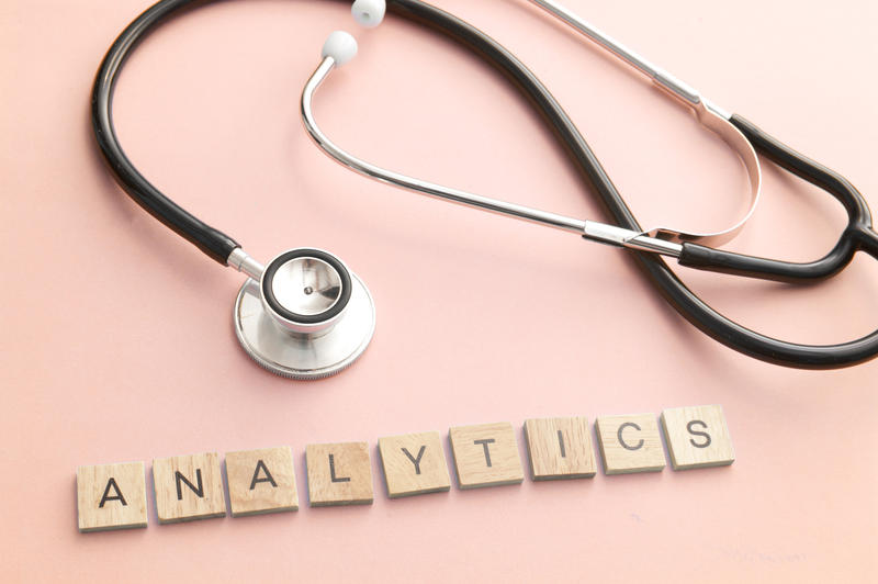 Website analytics concept with doctor stethoscope and little square wooden blocks over light pink background