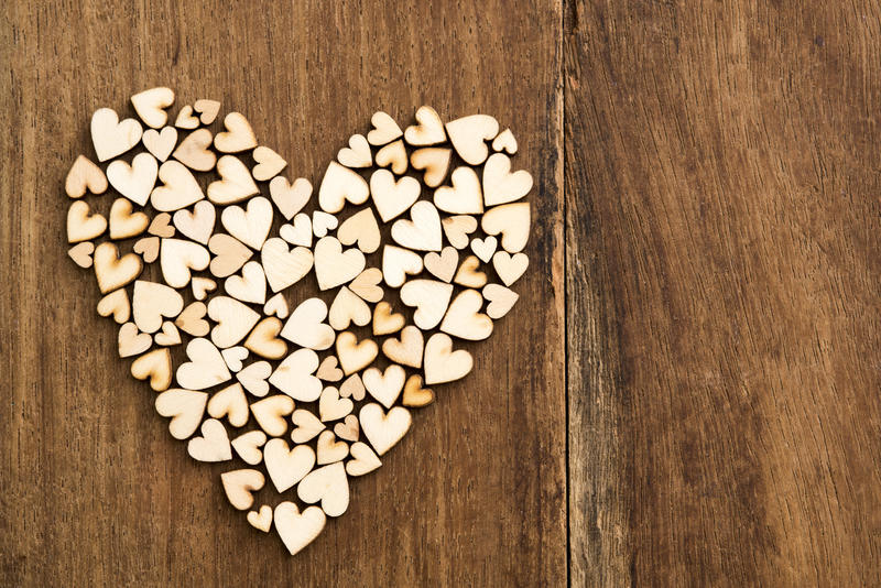 Small wooden hearts forming a larger heart shape on a rustic wood background with copy space for love and romance themes, Valentines or an anniversary