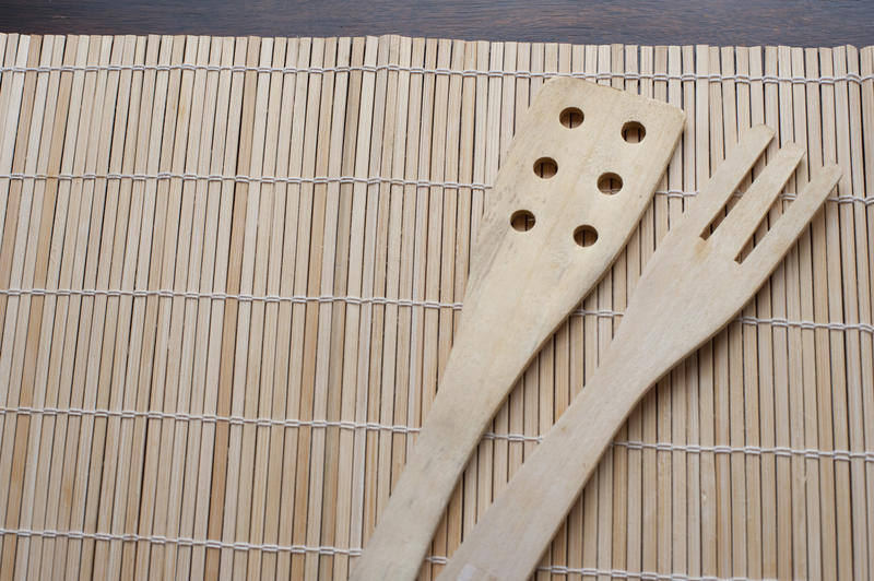 Plain wooden serving fork and spatula on a bamboo mat with copy space or placement space for food