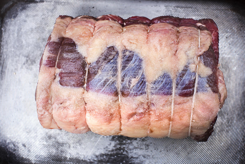 A close up of uncooked trussed beef shoulder ready for roasting.