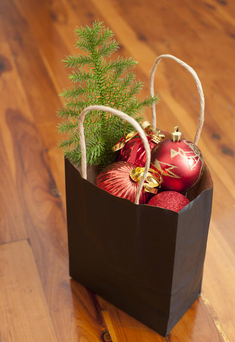 Paper bag filled with colorful red Christmas decorations and a small tree to decorate the house interior over the holiday season