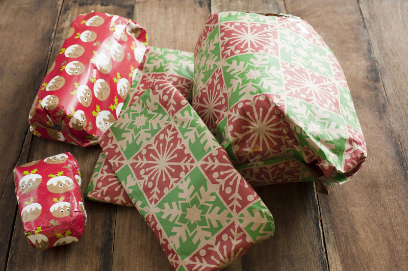 Pile of Christmas wrapped gifts on a wooden table in close up to celebrate the holiday season