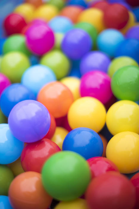 A close up of bright, multicoloured plastic balls in an amusement park ball pit.