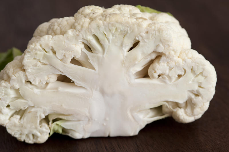 White cauliflower cut in half, viewed in close-up on dark background