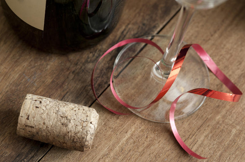 Party background concept with cork and glass tied with a festive red ribbon alongside a bottle of wine pr champagne