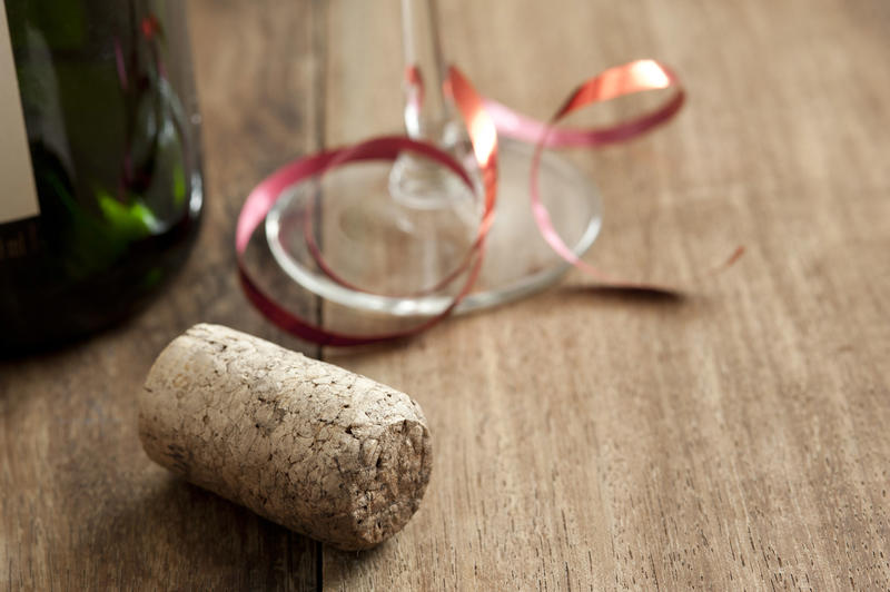 Party copy space with glass tied with a red ribbon, cork and bottle over a wooden background with copy space