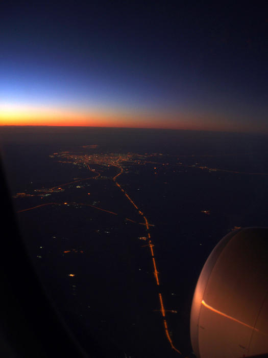 City lights and sunset sky as seen from the plane with turbine engine in foreground