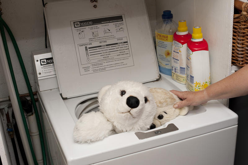 Person sanitizing plush stuffed kids toys in a washing machine in a concept of infection control during the coronavirus pandemic
